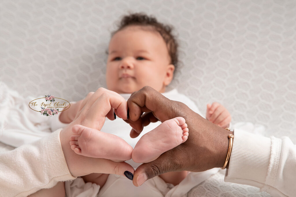 baby girl feet in parents hands heart shape